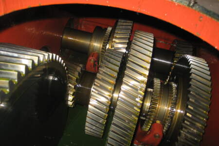 Große geölte Zahnräder in einem geöffneten Industriegetriebe, Detailansicht der mechanischen Kraftübertragung.