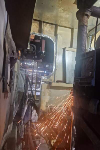 Innenraum mit Metallstruktur und intensivem Funkenflug beim Schneiden oder Schweißen, Gerüst und technische Bauteile sichtbar.